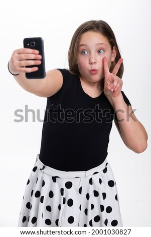 A young girl making a peace sign and pouting for camera.