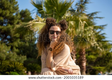 Beautiful girl with curls on the background of a palm tree