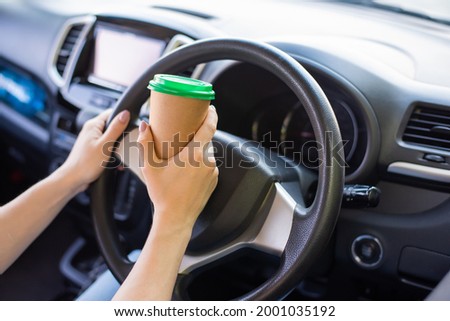 A faceless woman is drinking coffee in a craft glass while driving. Take a hot tonic drink to take away