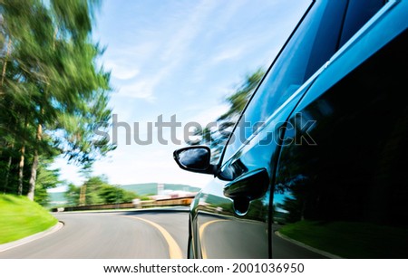 Mirror view of speeding car with blurred road.