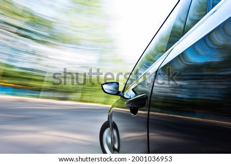 Mirror view of speeding car with blurred road.