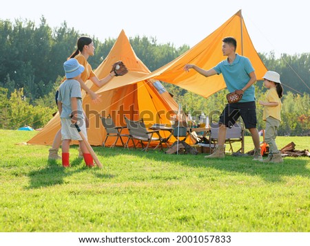 Happy family of four playing baseball in the park high quality photo