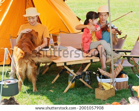 Happy family of three and pet dog playing violin outdoors high quality photo