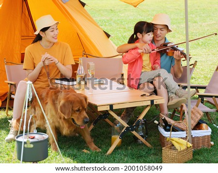 Happy family of three and pet dog playing violin outdoors high quality photo