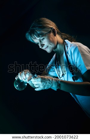 Middle aged female doctor pouring liquid into a lab flask