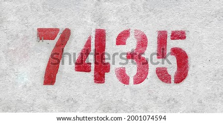 Red Number 7435 on the white wall. Spray paint. Number seven thousand four hundred thirty five.