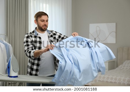 Young man with shirt after ironing at home