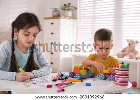 Cute children coloring drawing and playing at table in room