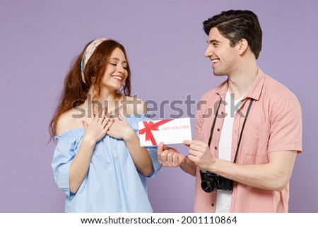 Two thankful traveler tourist woman man couple in shirt give gift voucher flyer mock up to girlfriend isolated on purple background Passenger travel abroad weekend getaway Air flight journey concept.