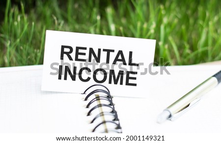 Card with text rental income on an open white fleece next to a pen