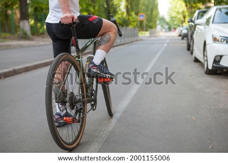 Unrecognizable cyclist standing on city road with his bicycle, copy space