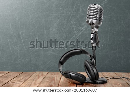 Retro style microphone and headphones on wooden table