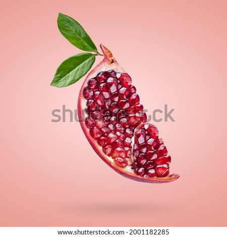 A ripe pomegranate with seeds and leaves flying in the air. Background with pomegranate fruit. Royalty-Free Stock Photo #2001182285