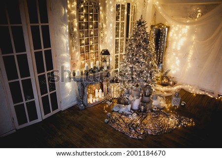 arm and cozy evening in Christmas room interior design,Xmas tree decorated by lights presents gifts,toys, deer,candles, lanterns, garland lighting indoors fireplace.holiday living room.magic New year