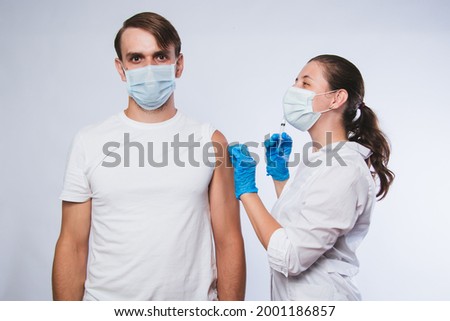 Girl doctor holds a syringe and makes an injection to a patient in a medical mask. Covid-19 or coronavirus vaccine. Masked man receiving coronavirus vaccination