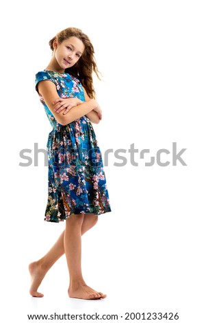 A beautiful little girl stands in the wind, her hair and clothes are developing greatly.