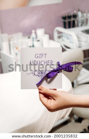 Beauty Salon Gift Certificate. Salon gift vouchers. Cosmetology Gift Card in female cosmetologist hands on beauty spa salon background
