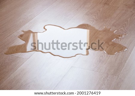 water puddle on laminate floor due to leakage Royalty-Free Stock Photo #2001276419