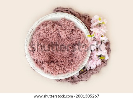 Beautiful basin furniture for newborn studio photoshoot with pink fur and white flowers decoration. Tiny designed handmade place for infant photo isolated on light background