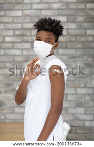 Covid-19 Vaccination concept. portrait  black african american young man Showing Arm With Plaster and thumb up or good sign after injection vaccine 