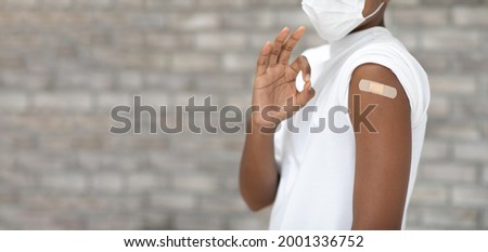 Covid-19 Vaccination concept. portrait  black african american young man Showing Arm With Plaster and thumb up or good sign after injection vaccine 