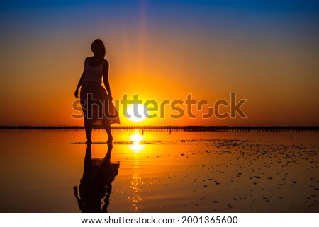 Silhouette of a girl on the background of sunset on a salt lake.