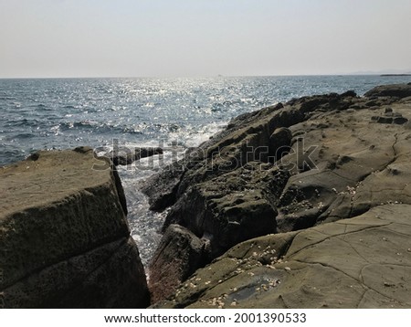 sea view with sparkling sea water and seashell surface big rocks and stones landscape photo