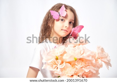 A young girl with a butterfly in the studio on a white background. Teen posing during a photo shoot. The concept of spring, summer, childhood, happiness