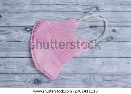 A pink face mask on grey wooden background. Pink face mask to protect from corona virus