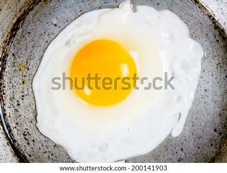 Egg fried on an old frying pan.