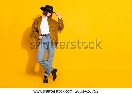 Photo of adorable cool young lady wear cowgirl outfit dark glasses arm headwear empty space isolated yellow color background