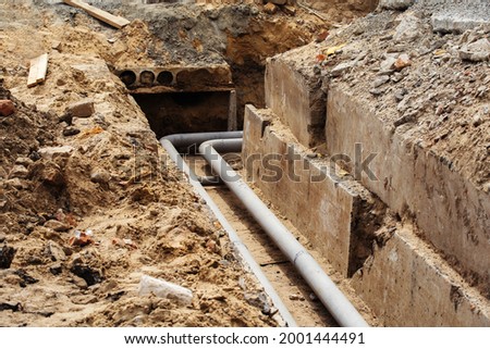 Replacing the old pipeline. Trench with replaced metal pipes and concrete base. Selective focus Royalty-Free Stock Photo #2001444491