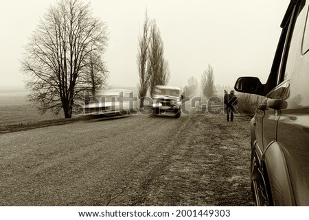A rural country road in the spring on asphalt one car overtakes another