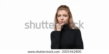 Sad and bored young woman in casual clothes, lean head on hand and stare indifferent at camera, standing upset against white background. Copy space