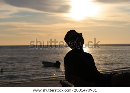 Nature and beauty concept. Orange sundown. silhouette at sunset.Young man sitting outdoors watching the sunset. Thinking and relaxing concept.man sit on a bench on a relax in nature sunset.