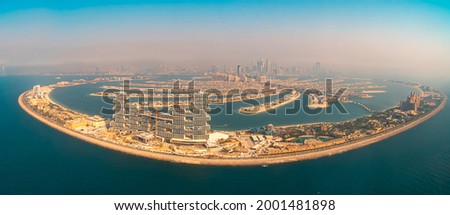 Panoramic aerial picture of the Palm Jumeirah artificial land in front of the Dubai coast on a sunny hazy day
