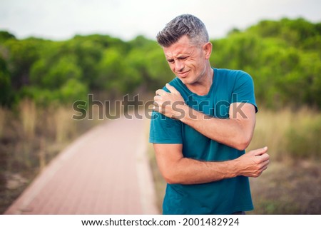 Shoulder pain. Man with arm injury outdoor. Healthcare and medicine concept Royalty-Free Stock Photo #2001482924