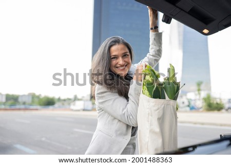 mature woman doing organic shopping and putting in trunk
