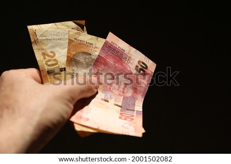 Hand holding South African money. This photo has selective focus. 