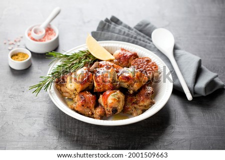 Roasted rabbit meat sliced with garlic, lemon and rosemary in a white plate, selective focus