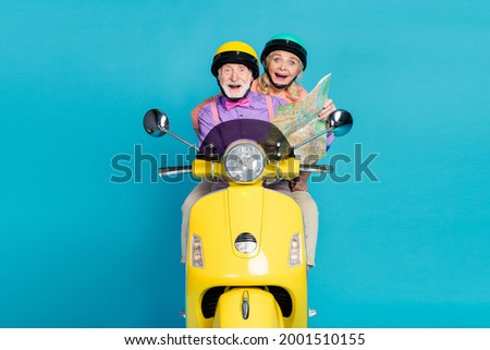 Photo of grey haired married couple ride bike happy hold map vacation trip isolated on pastel blue color background