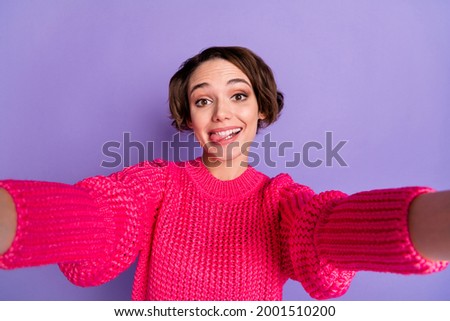 Photo of young cheerful girl happy smile playful bite tongue make selfie isolated over purple color background