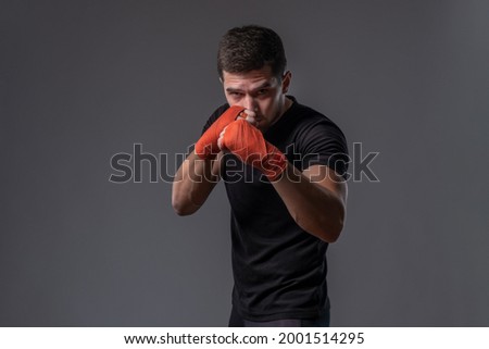 Focused young fighter with wrapped hands standing in orthodox stance Royalty-Free Stock Photo #2001514295