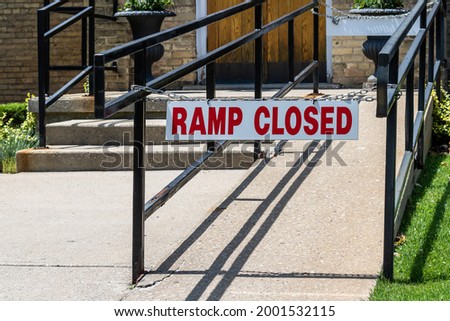 Red and white sign stating 'ramp closed'. Chained to black iron handrails. In front of church entrance. 