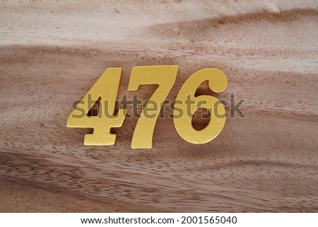 Gold Arabic numerals 476 on a dark brown to off-white wood pattern background.