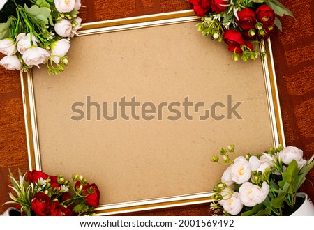 Empty gold picture frame with red and white flowers 