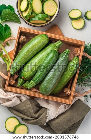 Young zucchini in a wooden box on a gray background. Top view, vertical. Royalty-Free Stock Photo #2001576746