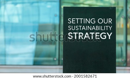 Setting our sustainability strategy  on a city-center sign in front of a modern office building	

