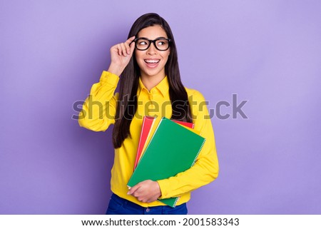 Photo of charming attractive young woman look empty space hold hands textbooks isolated on purple color background