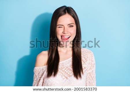 Photo of funky flirty young woman lick teeth tongue wink eye smile isolated on blue color background